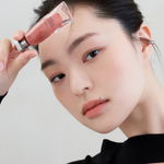 Model wearing Muzigae Mansion Objet Liquid Lip Tint in Barely 001, demonstrating the shade in natural lighting