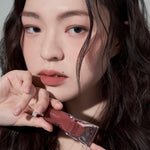 Model wearing Muzigae Mansion Objet Liquid Lip Tint in Stranger 003, demonstrating the shade in natural lighting