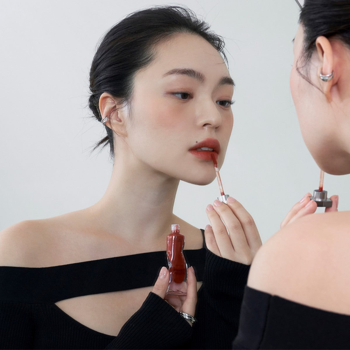 Model wearing Muzigae Mansion Objet Liquid Lip Tint in Notable 006, demonstrating the shade in natural lighting