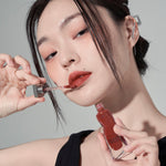 Model wearing Muzigae Mansion Objet Liquid Lip Tint in Chillin 007, demonstrating the shade in natural lighting