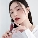 Model wearing Muzigae Mansion Objet Liquid Lip Tint in Perception 009, demonstrating the shade in natural lighting