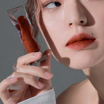 Model wearing Muzigae Mansion Objet Liquid Lip Tint in Undone 010, demonstrating the shade in natural lighting