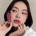 Model wearing Muzigae Mansion Objet Liquid Lip Tint in Symbol 012, demonstrating the shade in natural lighting