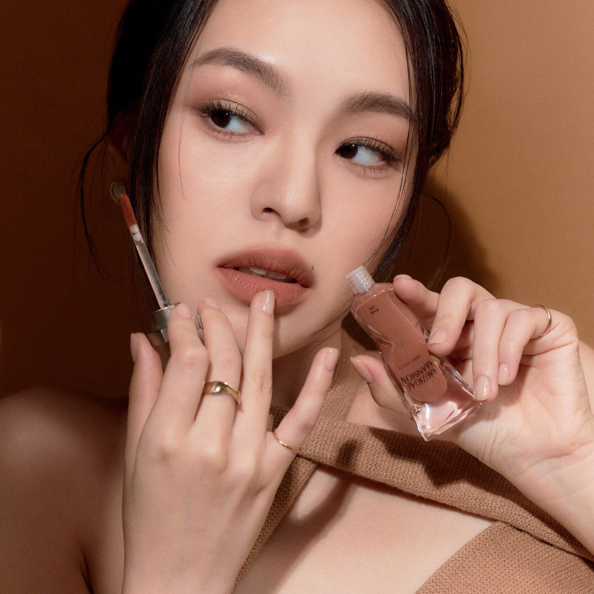 Model wearing Muziage Mansion Objet Liquid Lip Tint in Pride 015, demonstrating the shade in natural lighting